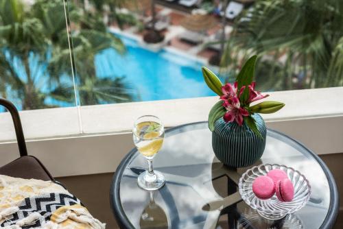 a glass table with a vase of flowers and a wine glass at Aria in Eilat