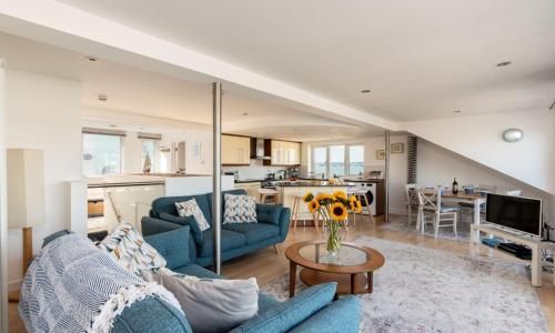 a living room with two blue couches and a kitchen at The Penthouse in Brixham