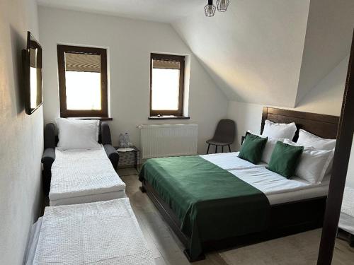 a bedroom with two beds and two windows at BORSIKA PENSIUNE & SPA in Căpîlniţa
