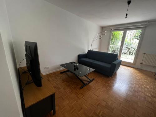 een woonkamer met een bank en een tv bij Appart calme avec jardin et parking. 15mn de Paris in Le Bourget