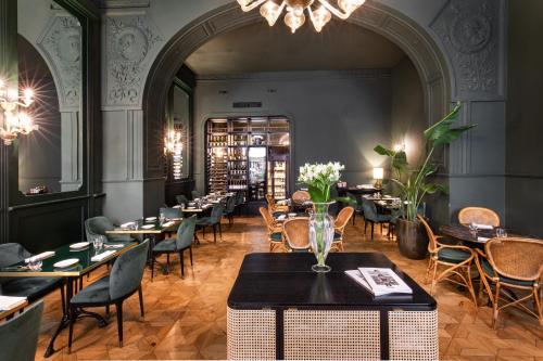 ein Restaurant mit Tischen, Stühlen und einem Kronleuchter in der Unterkunft Hotel Continentale in Triest