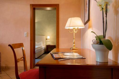 a room with a desk with a lamp and a mirror at Hotel am Luisenplatz in Potsdam