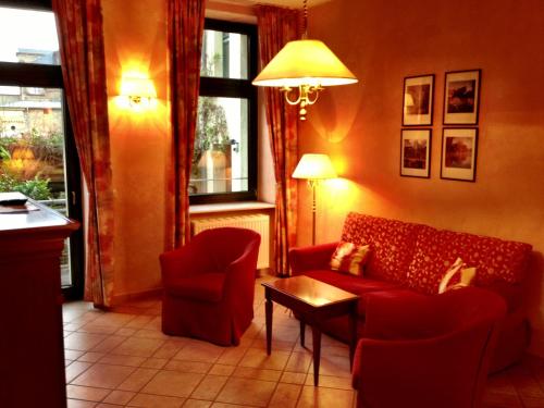 a living room with a red couch and two chairs at Hotel am Luisenplatz in Potsdam