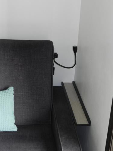 a couch sitting next to a wall with a wooden shelf at Le Lobellia à Sainte Clotilde centre in Sainte-Clotilde