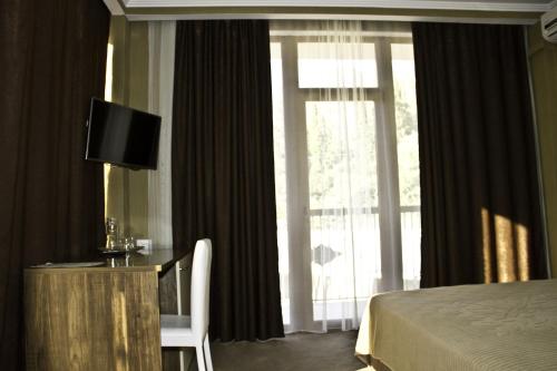 Habitación de hotel con cama, TV y ventana en Palma Hotel, en Gagra