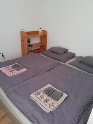 twee bedden met paarse lakens en handdoeken erop bij Relax apartman in Nagykanizsa