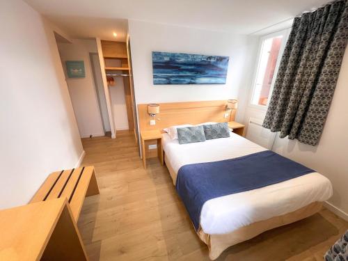 a small room with a bed and a desk and window at Auberge Les Tilleuls in Saint-Jorioz