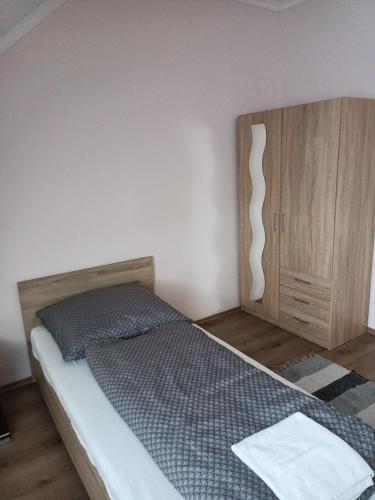 a bedroom with a bed and a wooden cabinet at Jázmin Vendégház in Nyírlövő