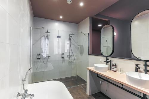 a bathroom with a shower and a sink and a tub at Hotel Halbert in Groningen
