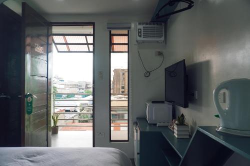 een slaapkamer met een bed en een deur naar een balkon bij Cebu Backpackers Hostel in Cebu City