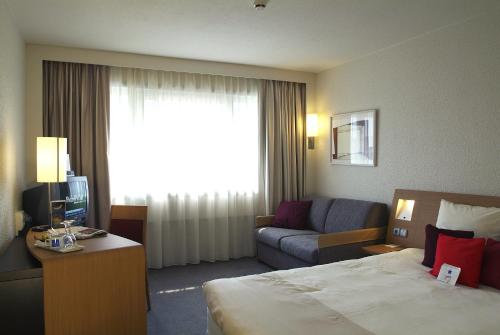 
a hotel room with a bed and a desk at Novotel Gent Centrum in Ghent
