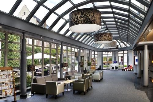 a lobby with chairs and tables and windows at Novotel Gent Centrum in Ghent