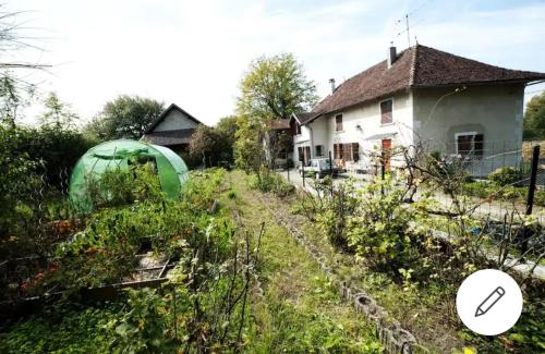 a garden in front of a house with a greenhouse at Chambre dans maison a la campagne in Pressins