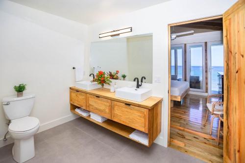 y baño con lavabo, aseo y espejo. en Wow! Views and more, fantastic 2 bedroom in West End - Villa Agua apts en Roatán