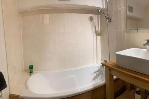 y baño con bañera blanca y lavamanos. en Appartement Alpe Huez 8 personnes centre station en LʼHuez