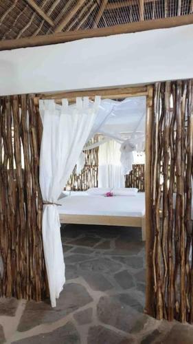 1 dormitorio con 1 cama con cortina y ventana en Tembo House - Rafiki Village en Watamu