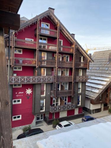 ein rotes Gebäude mit Balkon auf der Seite in der Unterkunft Appartamento Stalle Lunghe in Prato Nevoso