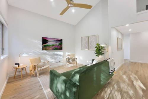 a living room with a green couch and a ceiling fan at On the Brook - Private 2 bed + loft and pool in Brisbane