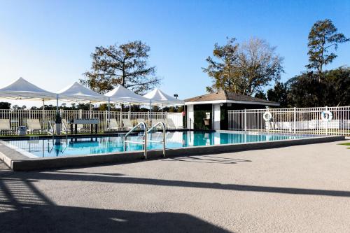 a swimming pool with white umbrellas next to at Palazzo Lakeside Hotel in Kissimmee
