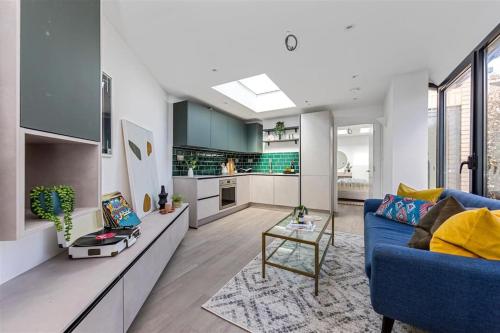 a living room with a blue couch and a kitchen at Cozy Leyton House with Garden and Small Terrace in London