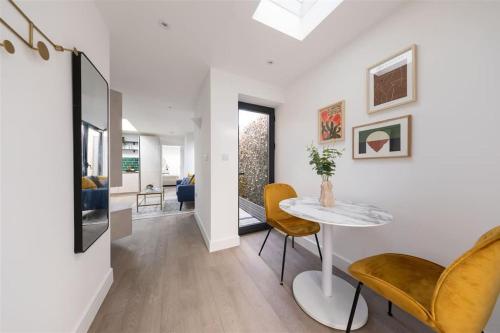 a living room with a table and yellow chairs at Cozy Leyton House with Garden and Small Terrace in London