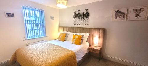Un dormitorio con una cama con almohadas amarillas y una ventana en George Hudson Court Apartments, en York