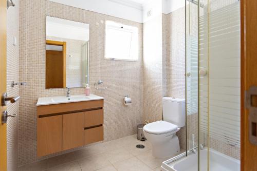 ein Badezimmer mit einem WC, einem Waschbecken und einem Spiegel in der Unterkunft Gardénia Apartment in Santa Luzia