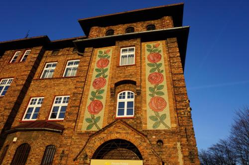 un edificio de ladrillo alto con flores pintadas en él en Muralowy apartament Katowice Nikiszowiec en Katowice