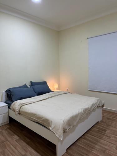 een witte slaapkamer met een groot bed met blauwe kussens bij شقه بغرفة نوم تسجيل دخول ذاتي in Ar Rākah