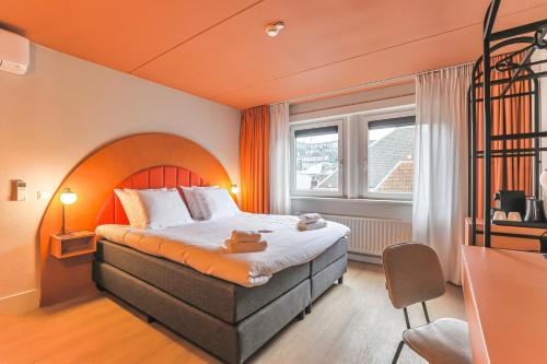 フローニンゲンにあるHotel Halbertのオレンジ色の壁のベッドが備わるホテルルームです。