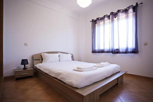 1 dormitorio con 1 cama con sábanas blancas y ventana en Quinta da Gomeira, en Cabanas de Tavira