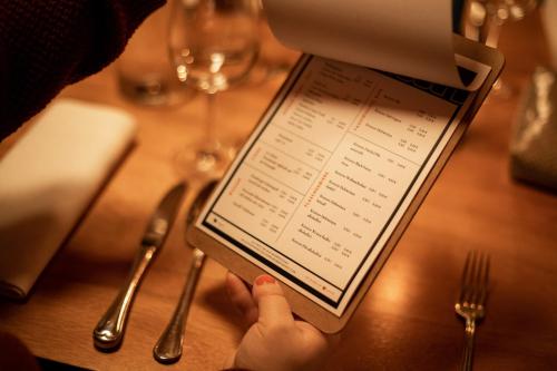 a person holding a tablet with a menu on a table at DAS SCHÖNE LEBEN Pop-Up Hotel in Hornberg