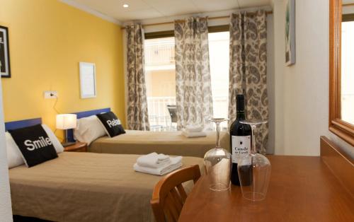 Pokój z 2 łóżkami i stołem z butelką wina w obiekcie Hostal Tierramar w El Arenal