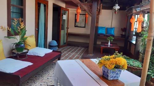 un porche con 2 camas y una mesa con flores. en The North Hotel, en Chiang Rai