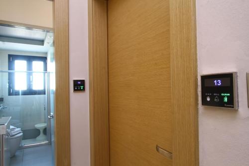 a door with a clock next to a bathroom at Ilioxenia Chios Studios & Apartments in Paralia Agias Foteinis