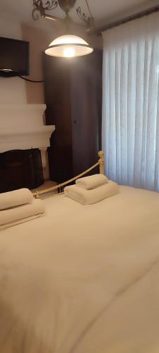 a bedroom with a bed with white sheets and a window at Αρχοντικό Ταξίμι (Μουντζουρίδη) in Argalasti