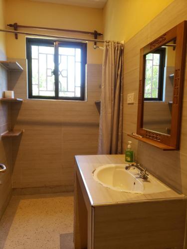 ein Bad mit einem Waschbecken, einem Spiegel und einem Fenster in der Unterkunft Bella Breeze1 - Diani Beach, Kenya in Diani Beach