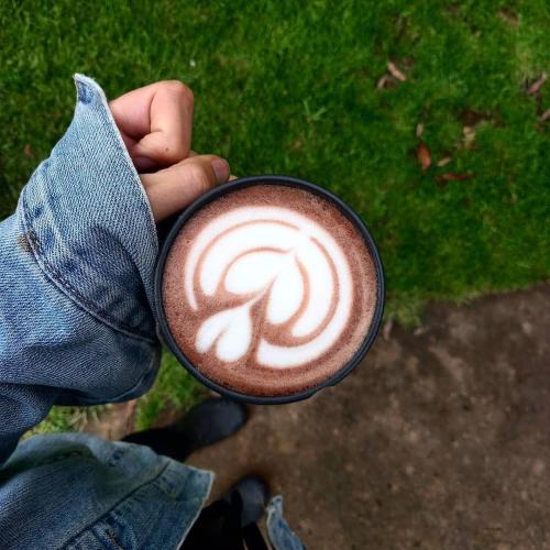 a person holding a cup of coffee with a swirl at The Old Mushroom Farm in Howick
