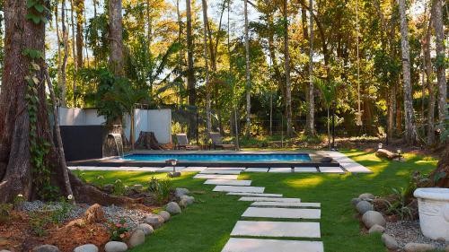 a backyard with a swimming pool and trees and grass at Olivia del caribe suite in Puerto Viejo