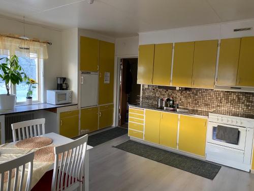 a kitchen with yellow cabinets and a table in it at Vindsvåning Höga Kusten in Kramfors