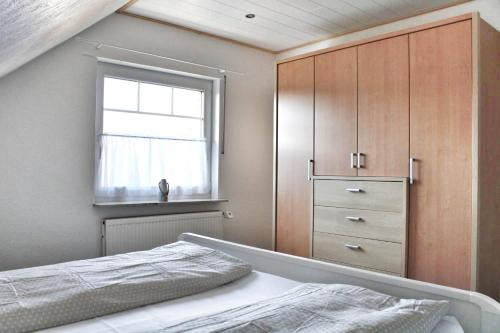 ein Schlafzimmer mit einem Bett, einem Fenster und einer Kommode in der Unterkunft Nordsee Anker Unsere moderne 87 qm Ferienwohnung mit zwei Schlafzimmer in Norden Ortsteil Ostermarsch in Norden