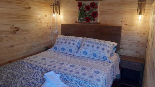 een slaapkamer met een bed met blauwe en witte lakens en kussens bij Cabaña del campo in Hornopiren