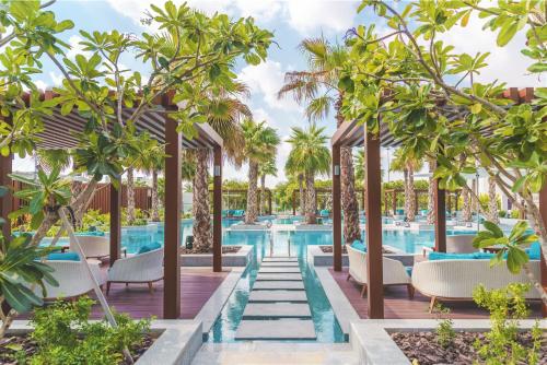 una imagen de una piscina en un complejo con sillas y árboles en Al Messila, A Luxury Collection Resort & Spa, Doha en Doha