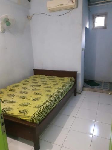 una camera da letto con un letto con una coperta gialla sopra di Hotel Griya Syar'i a Pekalongan