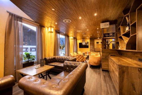 a living room with leather couches and a table at Schlosshotel Lacknerhof in Flachau
