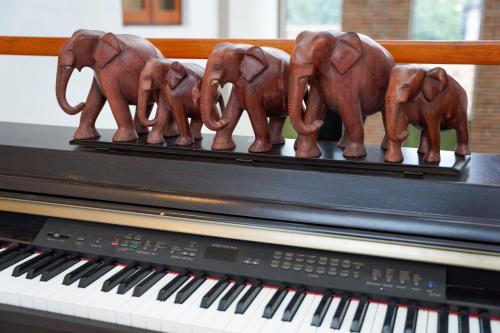 a group of elephants figurines sitting on top of a piano at J Leaf Hotel By Blue Bird in Negombo