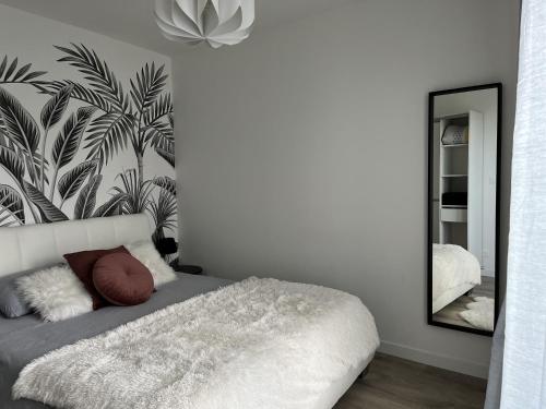 1 dormitorio con cama blanca y espejo en Cottage l'Echappée Belle, en Saint-Amand-les-Eaux