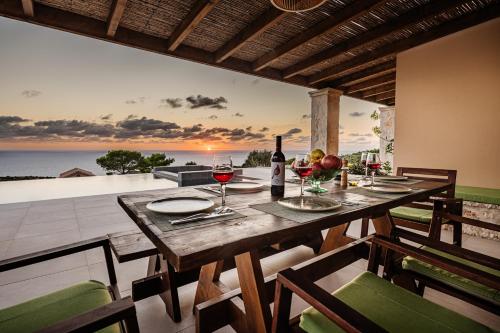 a table with wine glasses on a patio with the ocean at Terra Lucis Mountain Residences in Agios Leon