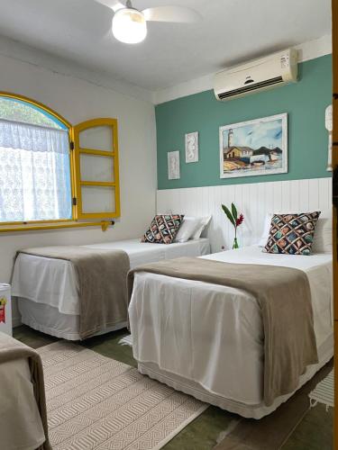 two beds in a room with green walls at Hospedaria do Marquês in Boicucanga
