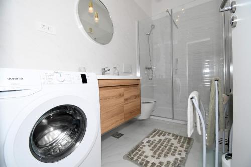 a white washing machine in a bathroom with a shower at Apartment Frida Rab in Banjol